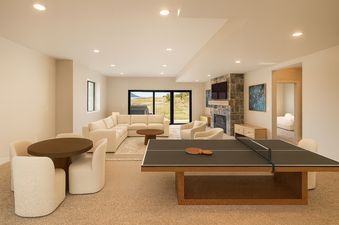 A spacious entertainment area in the Keetly Vista with a comfortable lounge area, a ping-pong table, and large windows offering views of the outdoors.