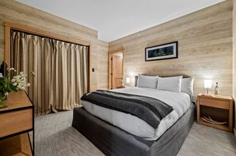 A cozy bedroom in Moose Creek 15 with wood-paneled walls, a queen-sized bed, and elegant, modern furnishings.