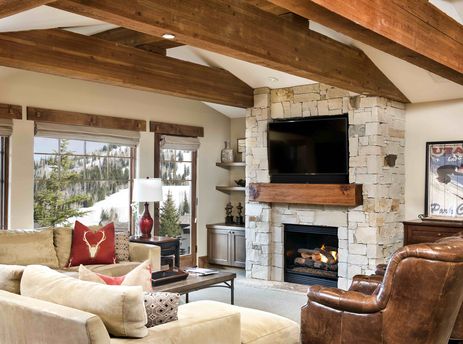 The Chateaux Four Bedroom Suite's spacious living room features a fireplace, comfortable seating, and large windows with stunning mountain views.