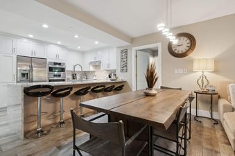 The kitchen and dining area features a large island with bar stools and a wooden dining table with seating.