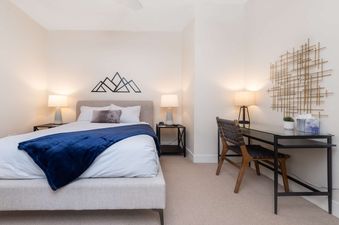 A modern and cozy bedroom with a queen-sized bed, stylish workspace, and warm lighting at Hideaway Haven.