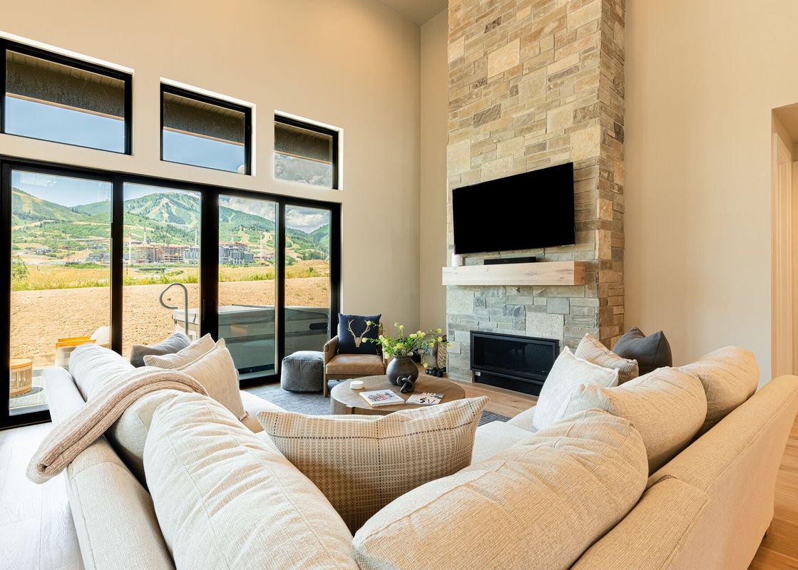 A modern and bright living area at Mayflower Lakeside 9506 with a large sectional sofa, stone fireplace, and mountain views.