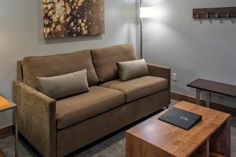 A cozy living area featuring a brown sofa, a wooden coffee table with a black book, and modern decor elements.