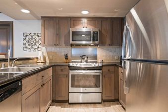 Modern kitchen with stainless steel appliances and wood cabinets in St James Place 121.