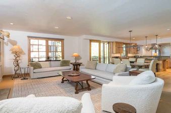 A large living room with two white couches, a coffee table, and a fireplace.