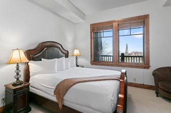 The bedroom of Grand Lodge Three Bedroom Deluxe 206 with a king-size bed, nightstands, and a window with views of the mountains.