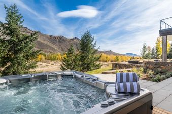 A private hot tub at Big Wood River Retreat with mountain and vibrant fall foliage views under a clear blue sky.