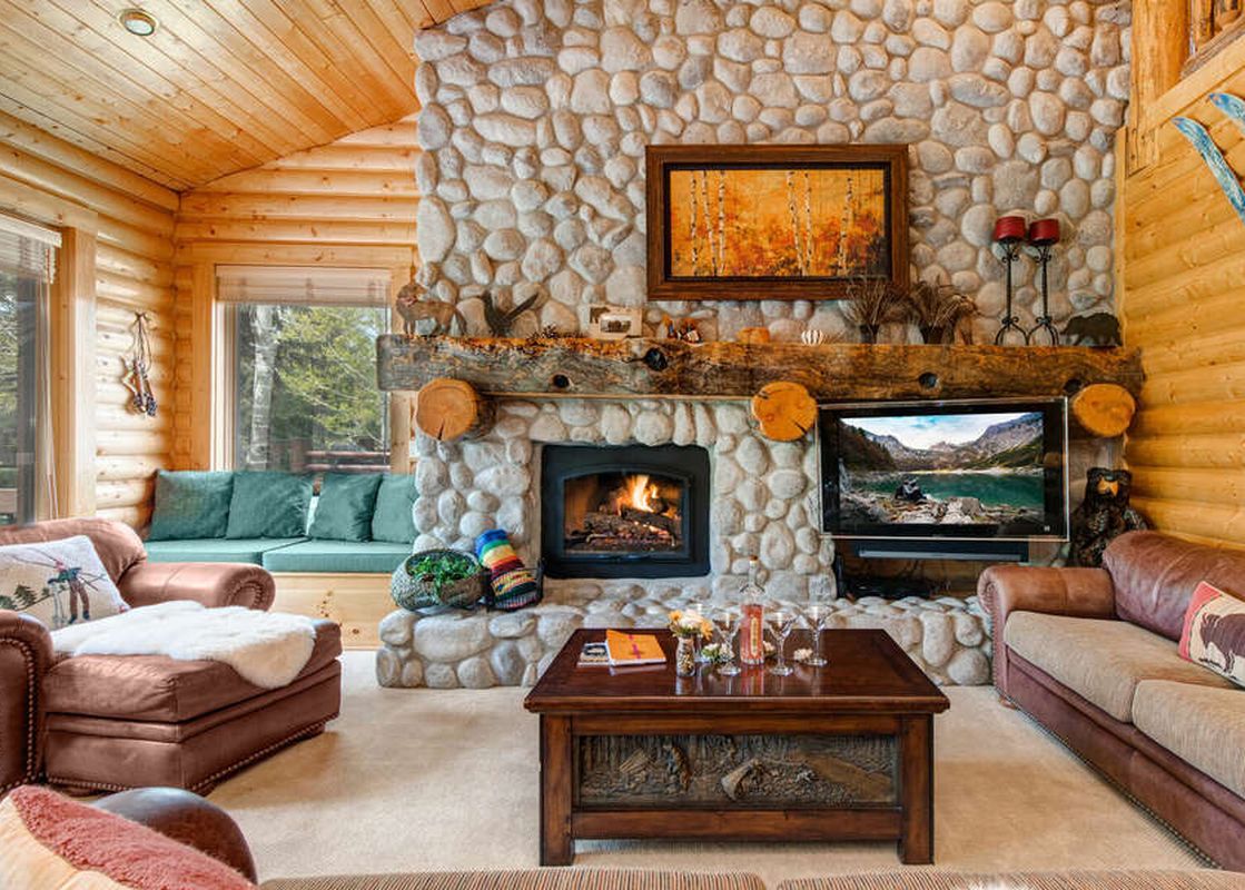 The Abode at Glenfiddich in Deer Valley offers a cozy living room with a stone fireplace.