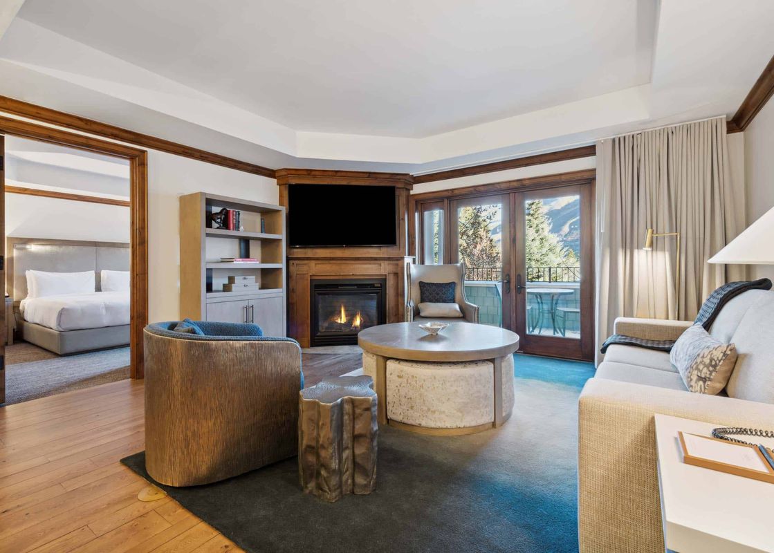 Living area in the Aspen 12B featuring a corner fireplace, cozy seating, and glass doors to a balcony.