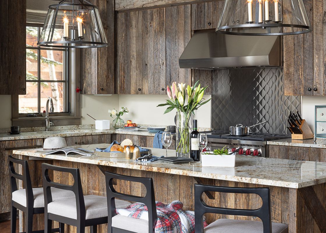 A rustic yet refined kitchen in Fish Creek Lodge 04, featuring rough-hewn wood, granite countertops, and modern appliances, perfect for gathering and entertaining.