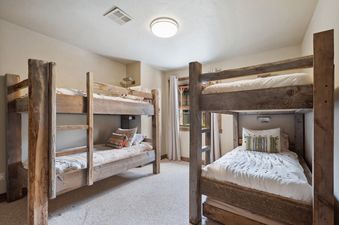 Two rustic wooden bunk beds are featured in the bunk room of Moose Jaw 34, complete with white bedding and decorative pillows.