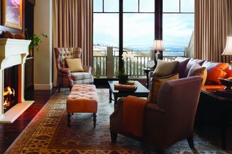 A luxurious and cozy living room with a fireplace and large windows showcasing a snowy mountain view.