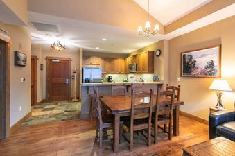 A dining area with a wooden table and chairs, next to a kitchen with stainless steel appliances.