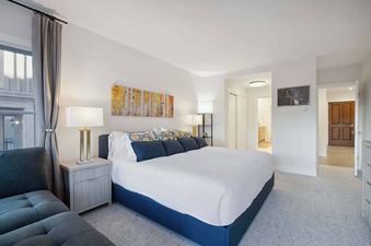 A bedroom with a king bed with blue and yellow pillows.