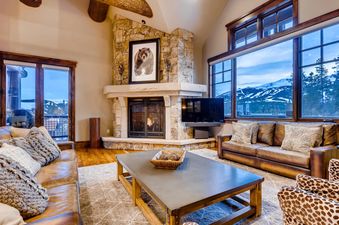 The living area at Monarch at Shock Hill features a stone fireplace, leather sofas, a coffee table, and large windows with mountain views.