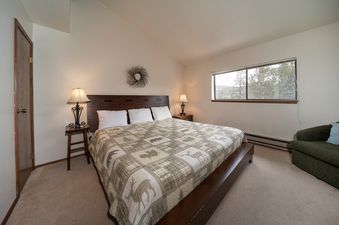 Bedroom with a king bed, side table, and window.
