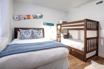 A cozy bedroom in Town Pointe A105 featuring a queen bed with blue accents and a rustic wooden bunk bed, decorated with ski-themed art.