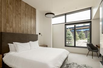 Moonlight Basin 11 Treeline's master bedroom features a large, modern bed, a window overlooking the forest, and a plush rug.