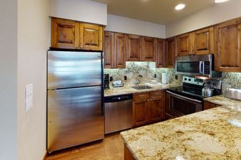 The kitchen in Manor Vail 336 features stainless steel appliances, granite countertops, and wood cabinetry.