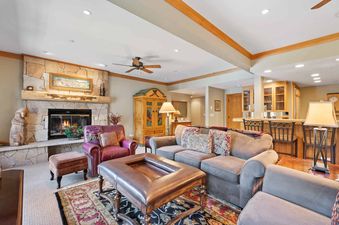 A cozy lounge area at The Charter E3305 features a stone fireplace, leather seating, and a bar area in the background.