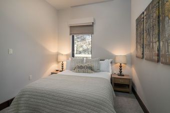 The Lumiere Four Bedroom Residence features a bedroom with a king-size bed, large windows, and bedside tables with lamps.
