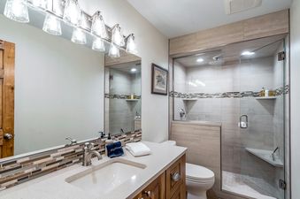 A bathroom with a white sink and vanity, a white toilet, and a walk-in shower.