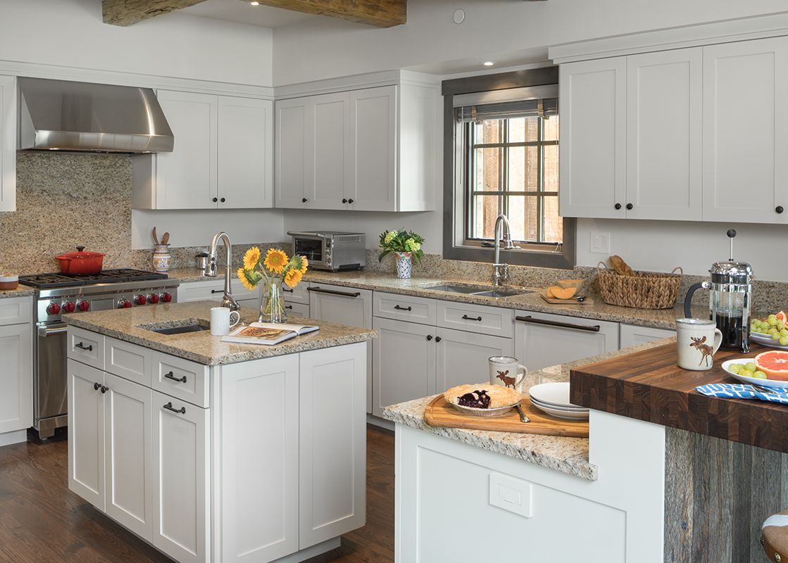 A spacious, well-lit kitchen featuring light cabinetry, granite countertops, two islands, and modern stainless steel appliances.