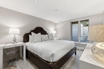 A modern and cozy bedroom featuring a large dark wood bed with white linens and stylish bedside lamps.