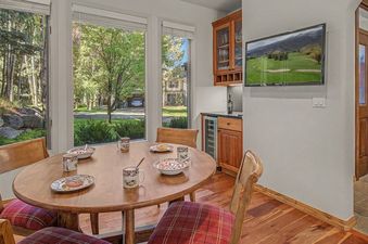 A bright dining area at Wild Iris Lodge with a round table, plaid chairs, and large windows looking outside.