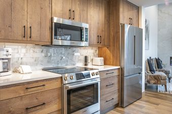The kitchen features wooden cabinets, stainless steel appliances, and a tiled backsplash.