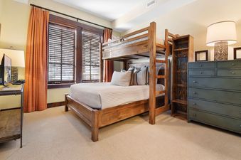 A cozy bunk room at Silver Star 4303 featuring a sturdy wooden bunk bed, a large green dresser, and warm lighting, creating a comfortable and inviting atmosphere for guests.