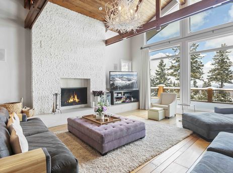The living room at 6977 Silver Lake Drive boasts a cozy fireplace and stunning outdoor views.