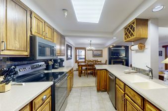 The kitchen at Torian Plum Plaza 202 features wooden cabinetry, stainless steel appliances, and a tiled backsplash, offering a functional and stylish space.
