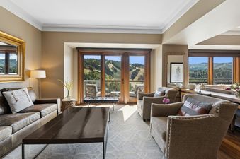 A spacious living room with floor-to-ceiling windows that offer panoramic views of the mountains.