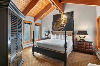The primary bedroom at Pinnacle 1358 features a four-poster bed, zebra artwork, and exposed wooden beams.