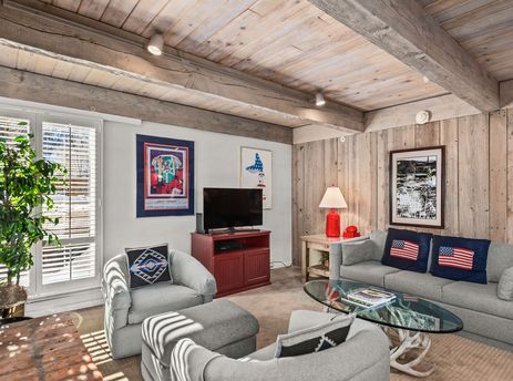 The cozy living room at Chateau Eau Claire Unit 1 features wood paneled walls and ceiling.