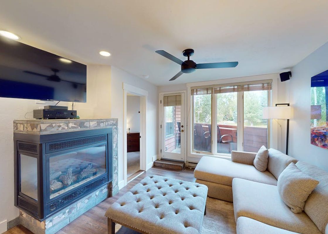 Living room with a fireplace, TV, sectional sofa, and balcony access at Trappeurs Lodge 1101.