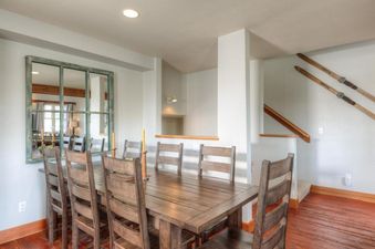 The dining area at Saddle Ridge Townhome Unit B1 features a large wooden table and chairs, with a rustic framed mirror on the wall.