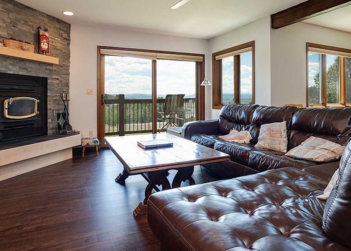 A cozy living room in the Ranch at Steamboat RA309 with a fireplace, comfortable sectional sofa, and a balcony with a view.