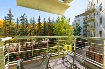 A private balcony at Alpine Vista King offers scenic views of autumn foliage and an adjacent building.