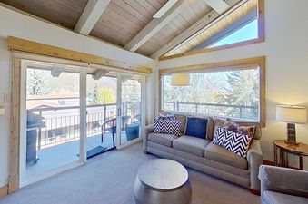 The living room at Crestwood 2307 features a comfortable couch, a stylish coffee table, and large windows that offer stunning views of the surrounding landscape.