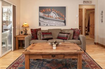 The inviting living area of Telemark 514 features a comfortable sofa with decorative pillows, a wooden coffee table, and a large window offering an exterior view of snow-covered surroundings.