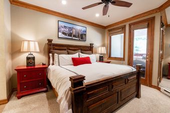 A bedroom with a king size bed and a view of the trees outside.