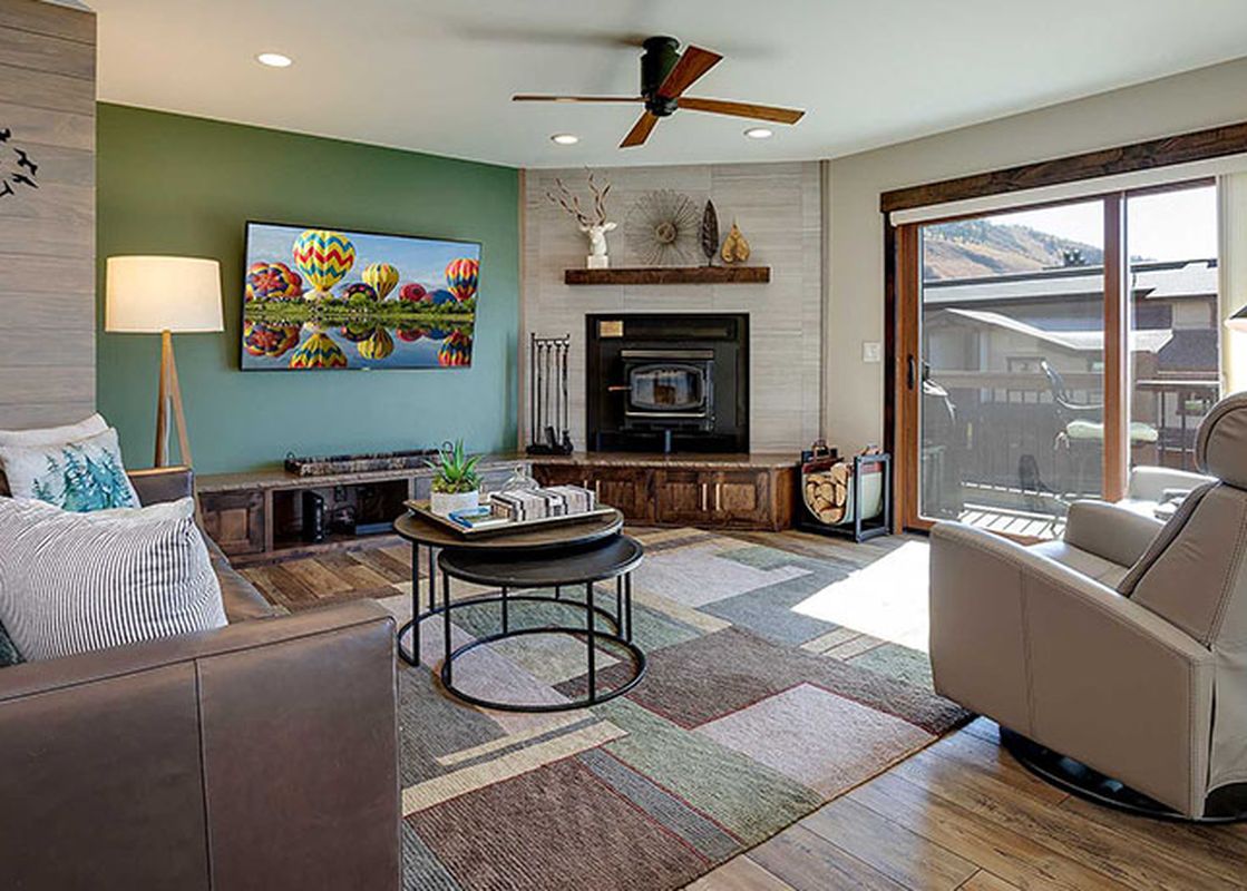 A cozy living room at Ranch at Steamboat RA217 featuring a fireplace, a beige leather sofa, a large window with mountain views, and unique decorative accents.