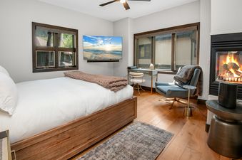 A luxurious king bedroom with a fireplace, flat-screen TV, desk, and large windows at Chateau Tremonte 8.