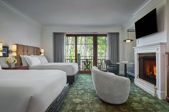 The Montage Deer Valley Accessible Resort View Queen Queen with Fire Pit features two queen beds, a fireplace, and a balcony with a view of lush greenery.