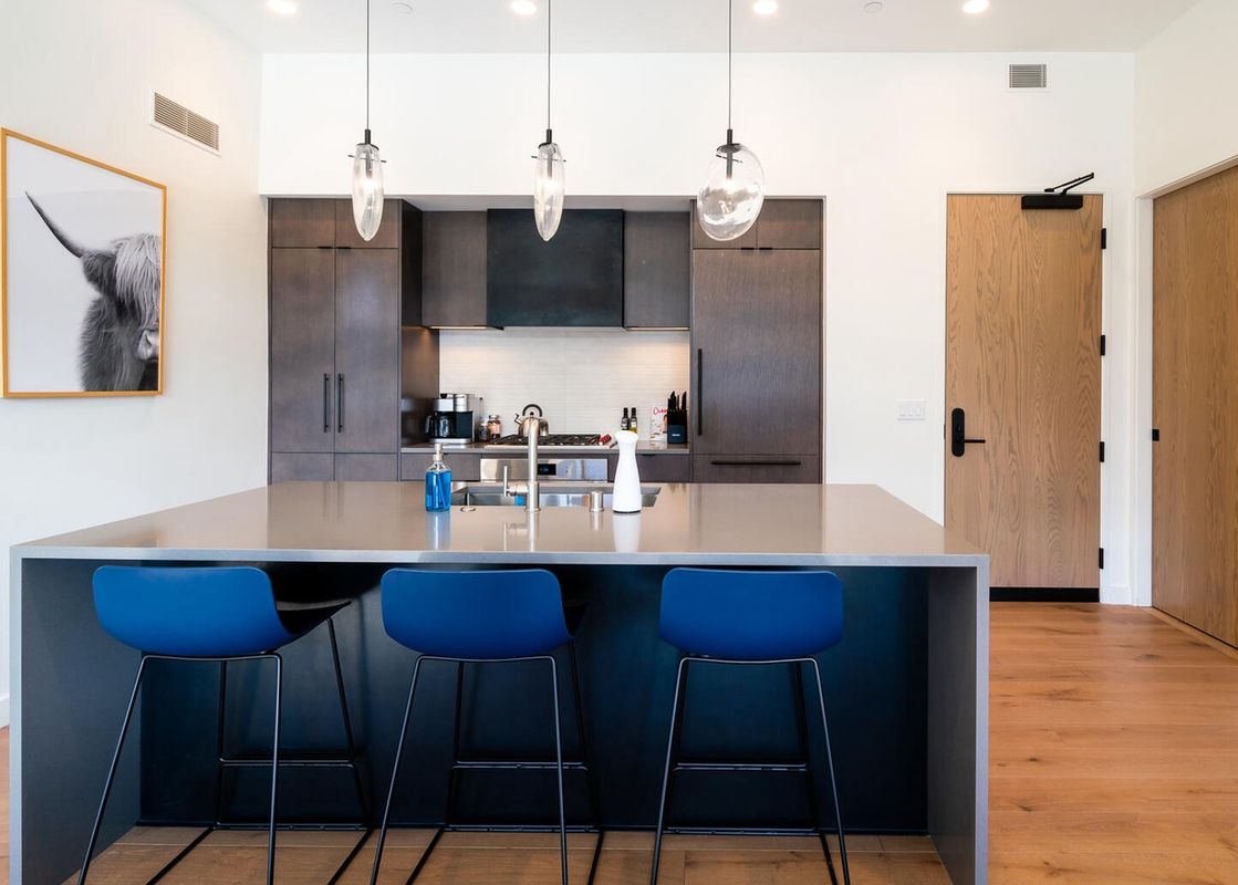 Modern kitchen with a sleek island countertop and three bar stools.