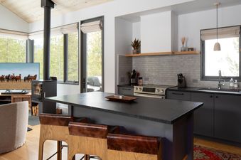 The kitchen in Moonlight Basin 27 Lake Cabin is modern and well-equipped with black countertops and gray cabinets.