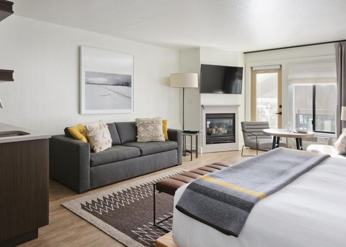 A modern and cozy king suite with a living area, fireplace, and bed at the Gravity Haus JH Premium King Suite.