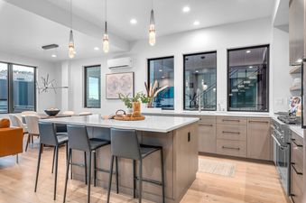 A modern kitchen with white countertops, stainless steel appliances, and a large island with bar stools.